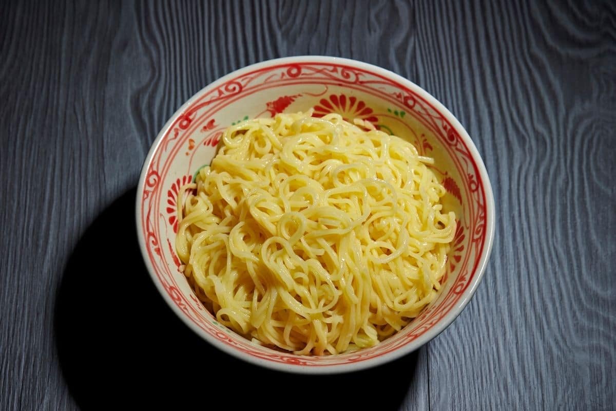 Red-white bowl of ramen noodles on a gray table.