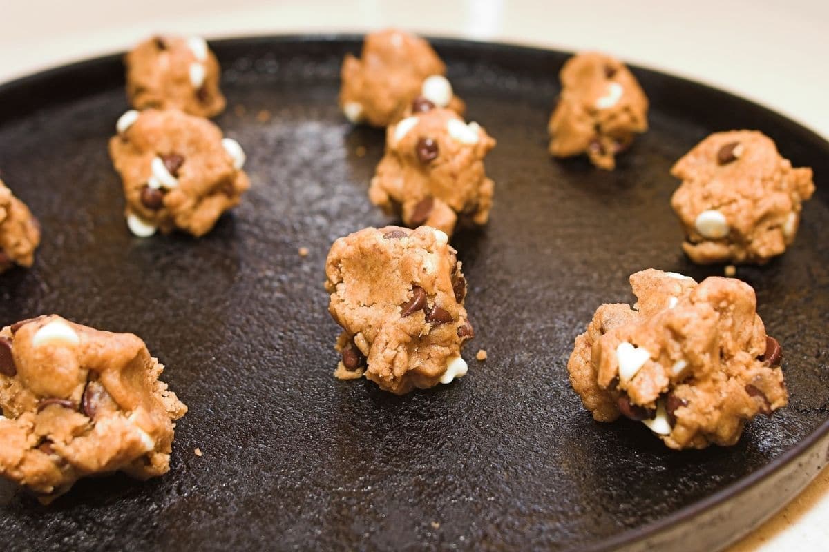Cookie dough on a black baking tray.