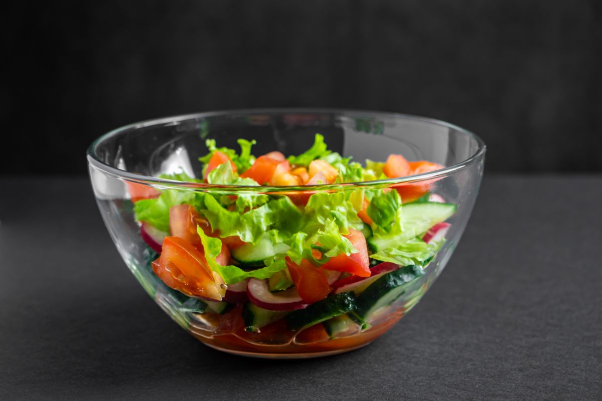 Glass bowl of vegetable salad on black background..