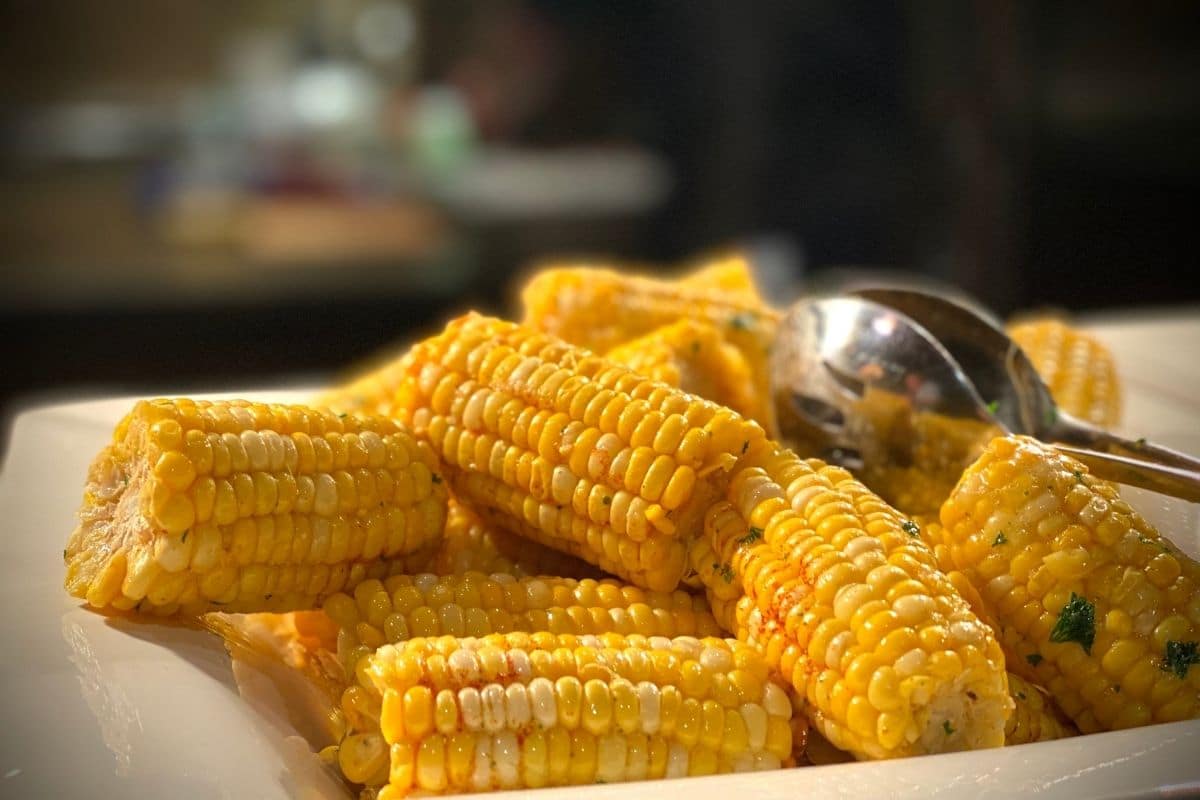 Piece of corn cobs on white plate with spoon.