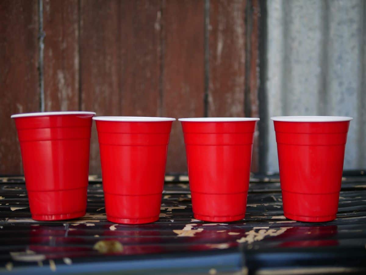 Four red solo cups on black table.