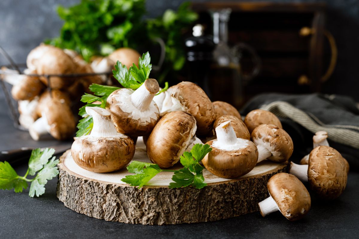 Fresh mushrooms on wooden cuttiing board on black table.