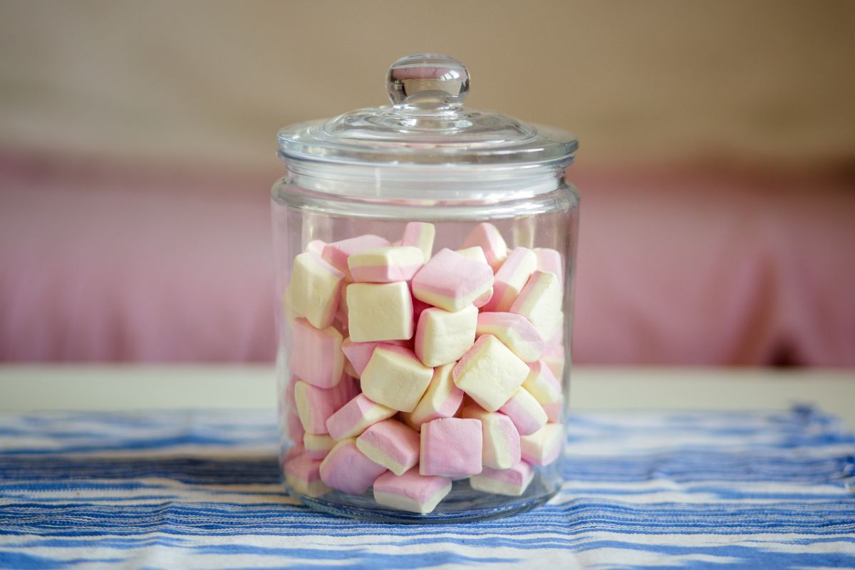 Glass jar full of a marshmallows on table.