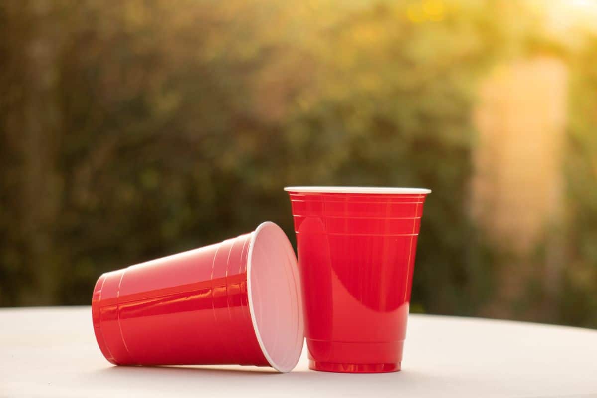 Two red solo cups on table on sunny day.