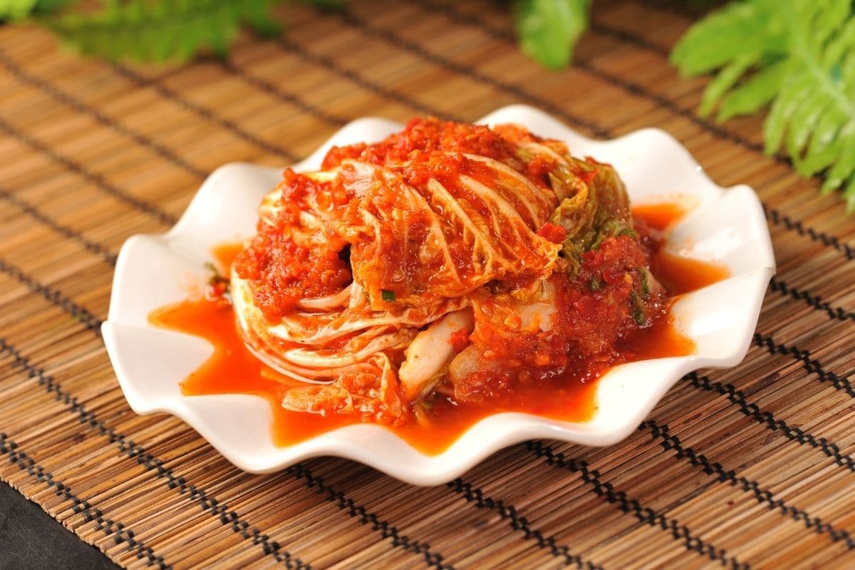 kimchi dish on white plate on wooden table.