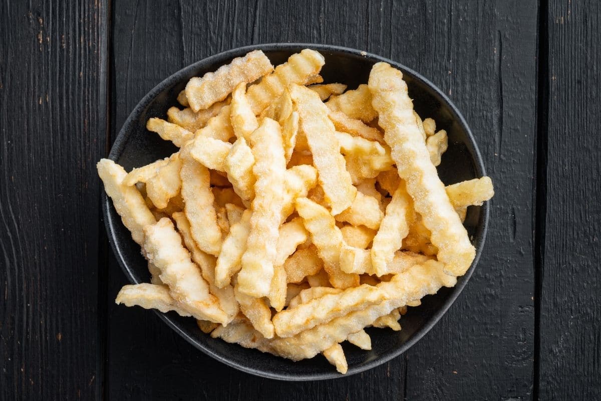 Bowl of frozen fries on a black table.