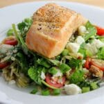 Salmon with vegetable salad on white plate.