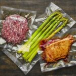 Asparagus,grinded meat, duck meat in vacuum sealed bags on table.