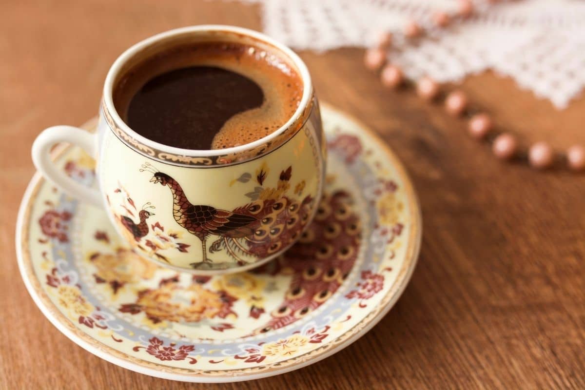 Cup of coffe on small plate on brown table.