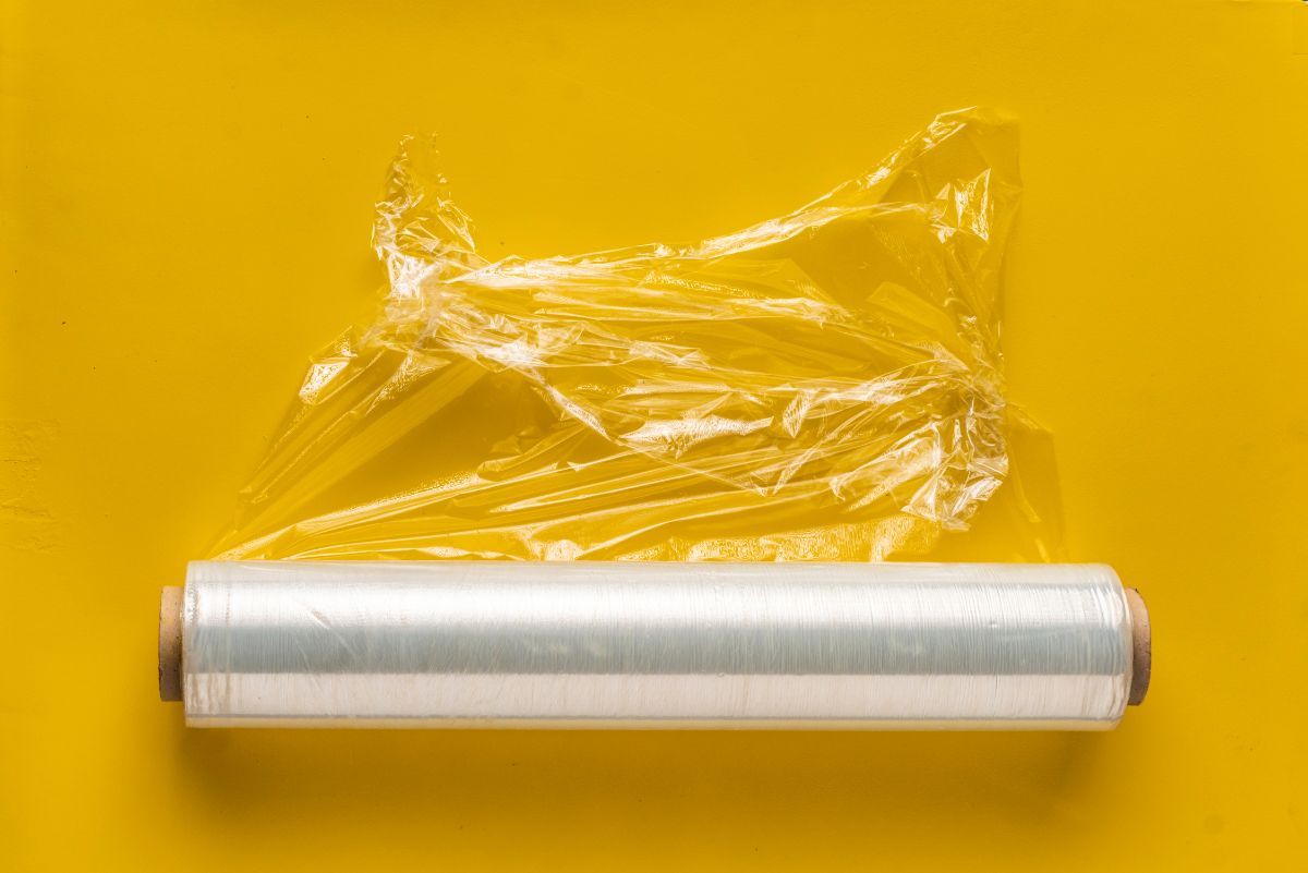Roll of plastic wrap on yellow background.