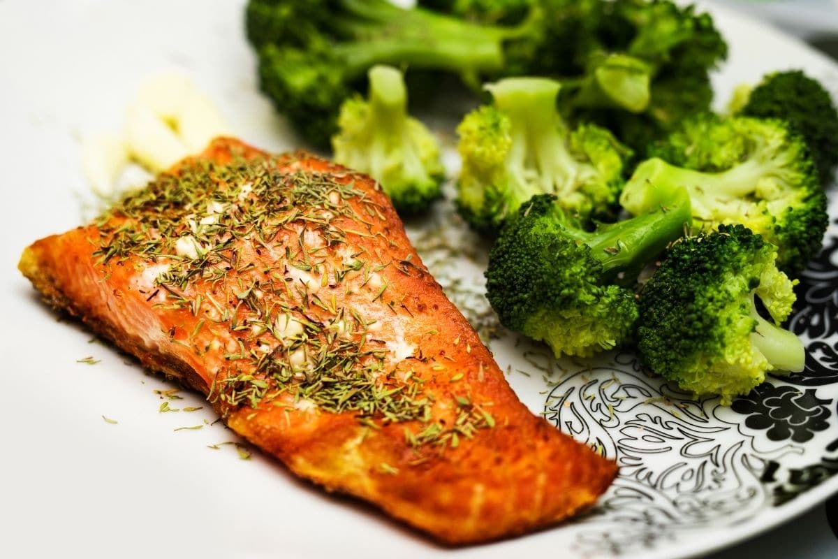 Salmon with broccoli on white plate.
