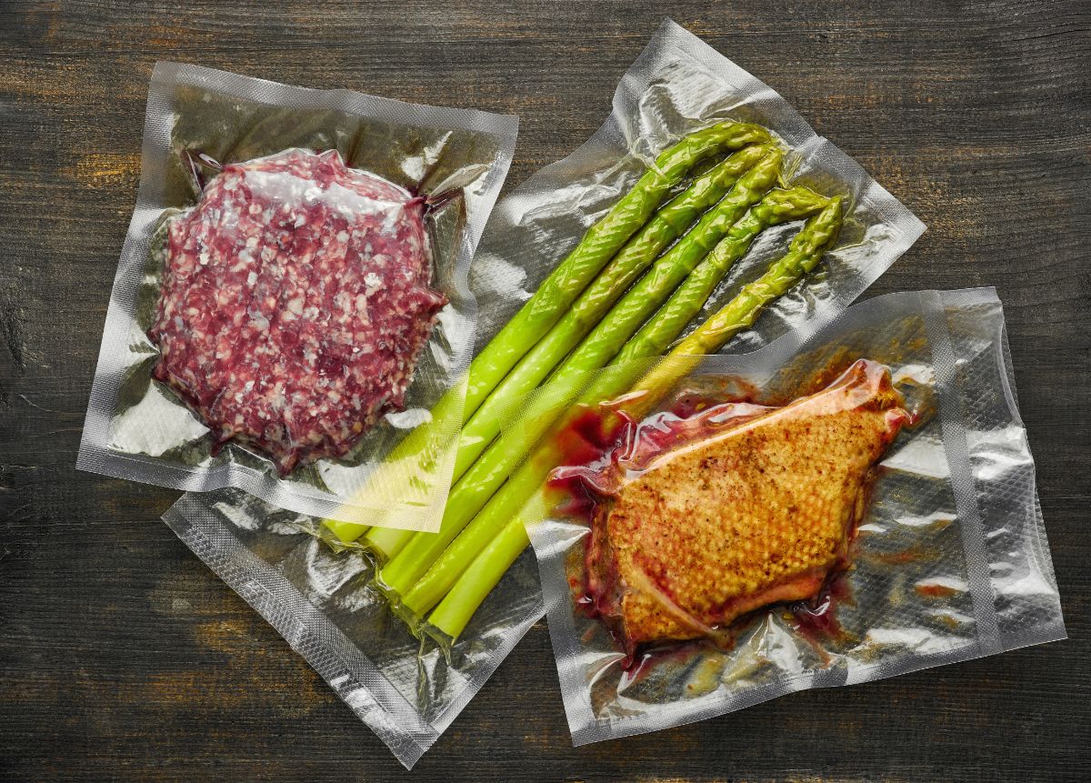 Asparagus, grinded meat and duck meat in vacuum sealed bags on table.