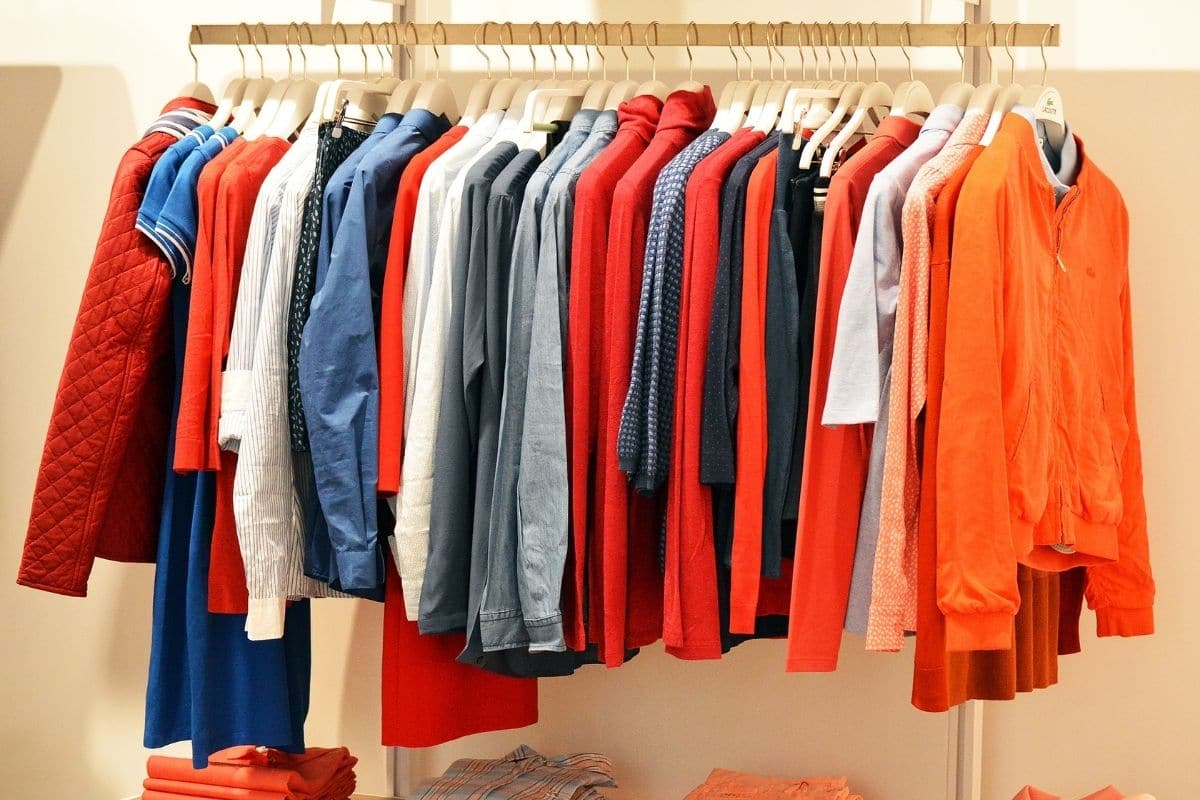 Different types of clothes hanging on coat racks.