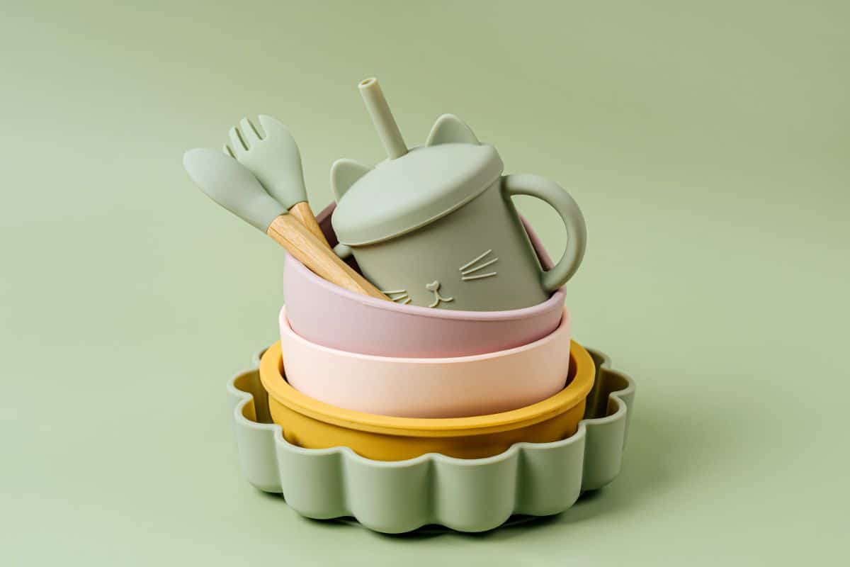 Silicone child tableware on green background.