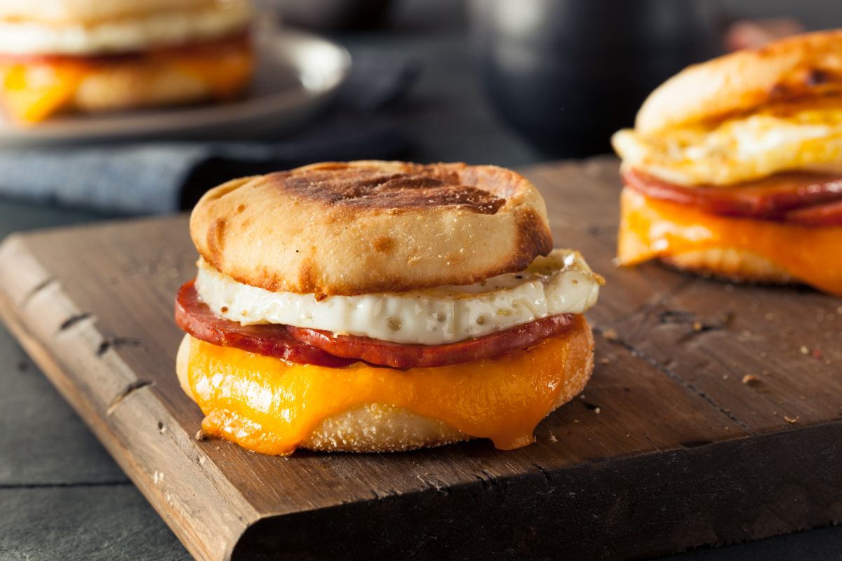 English muffin with egg and cheese on wooden board