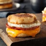 English muffin with cheese. egg on wooden cutting board.