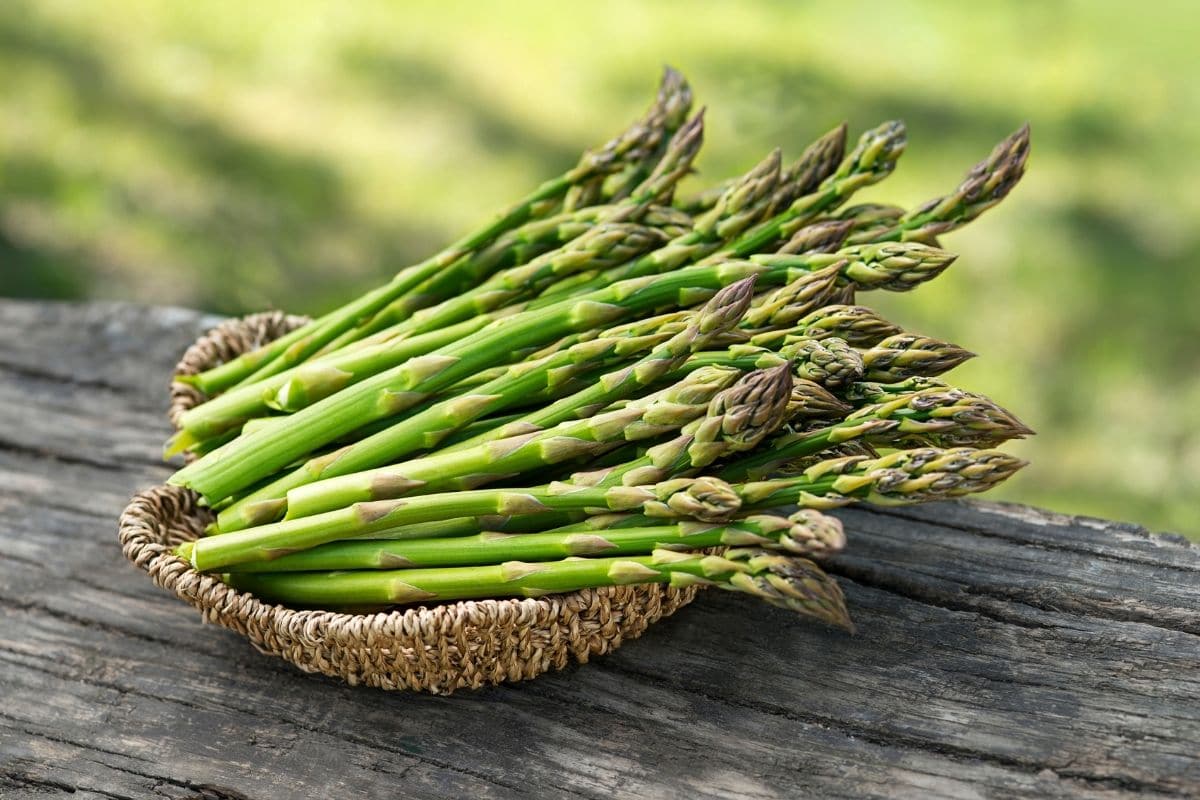 Basket of fresh asparagus on wooden table