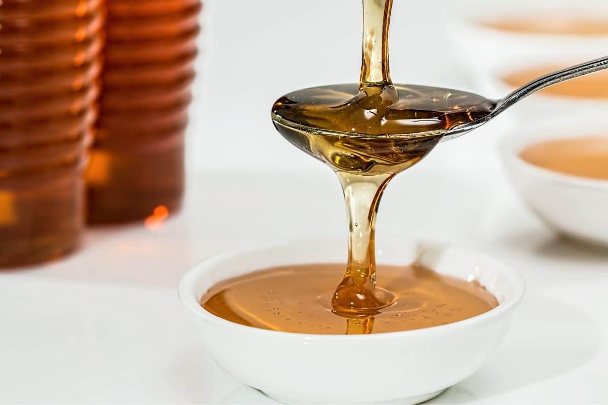 Honey poured on spoon and into small white bowl