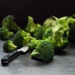 Fresh raw broccoli on black table with knife