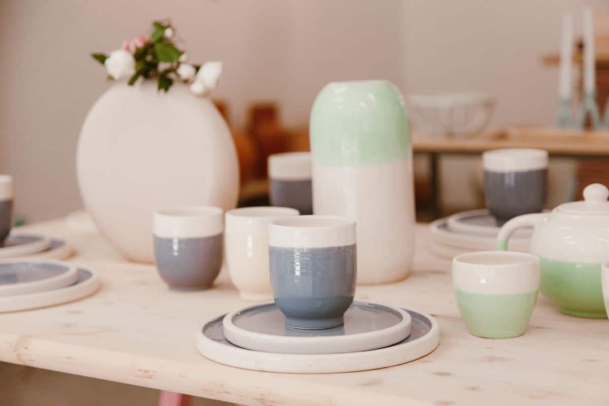 Ceramic cups, plates on wooden table with other dinerware