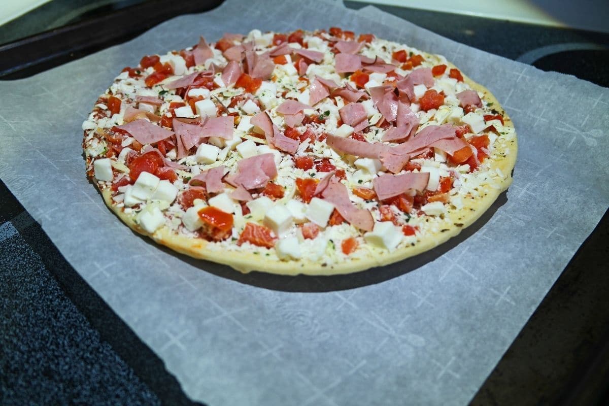 Frozen pizza on baking paper.