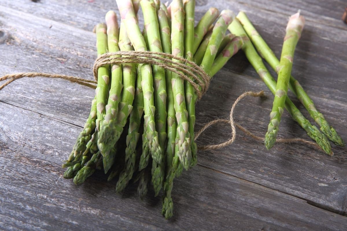 Stack of fresh asparagus on wooden table