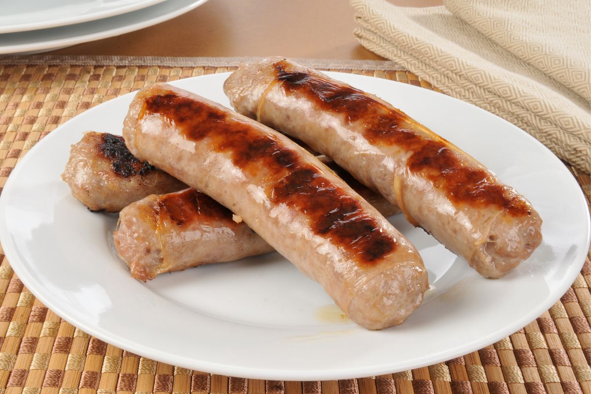 Bunch of sausages on white plate on table