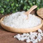 Epsom salt on wooden plate with spoon on table