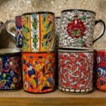 Colorful porcelain cups on wooden shelf