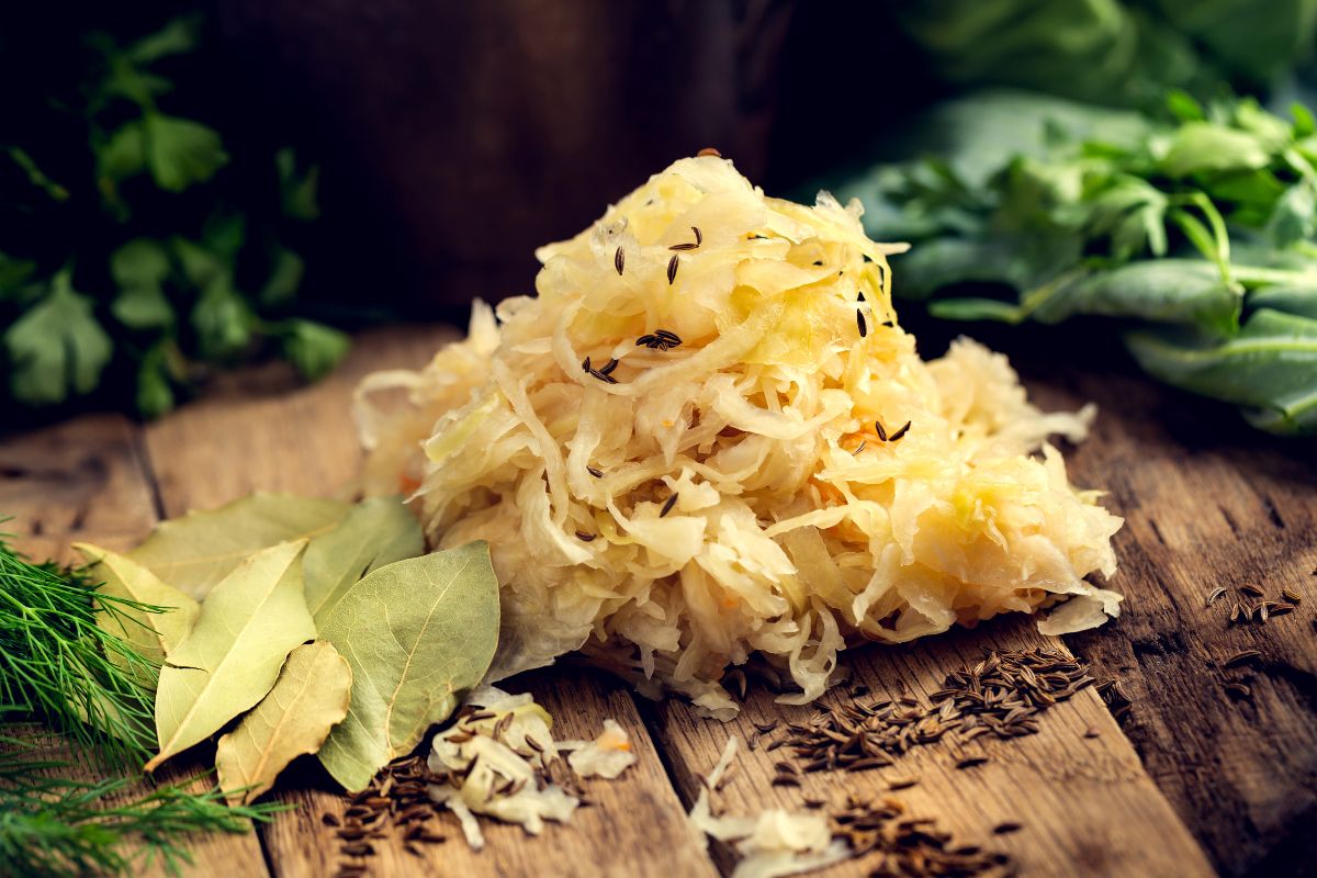 Fresh Sauerkraut on wooden board with seasoning and ingredients around