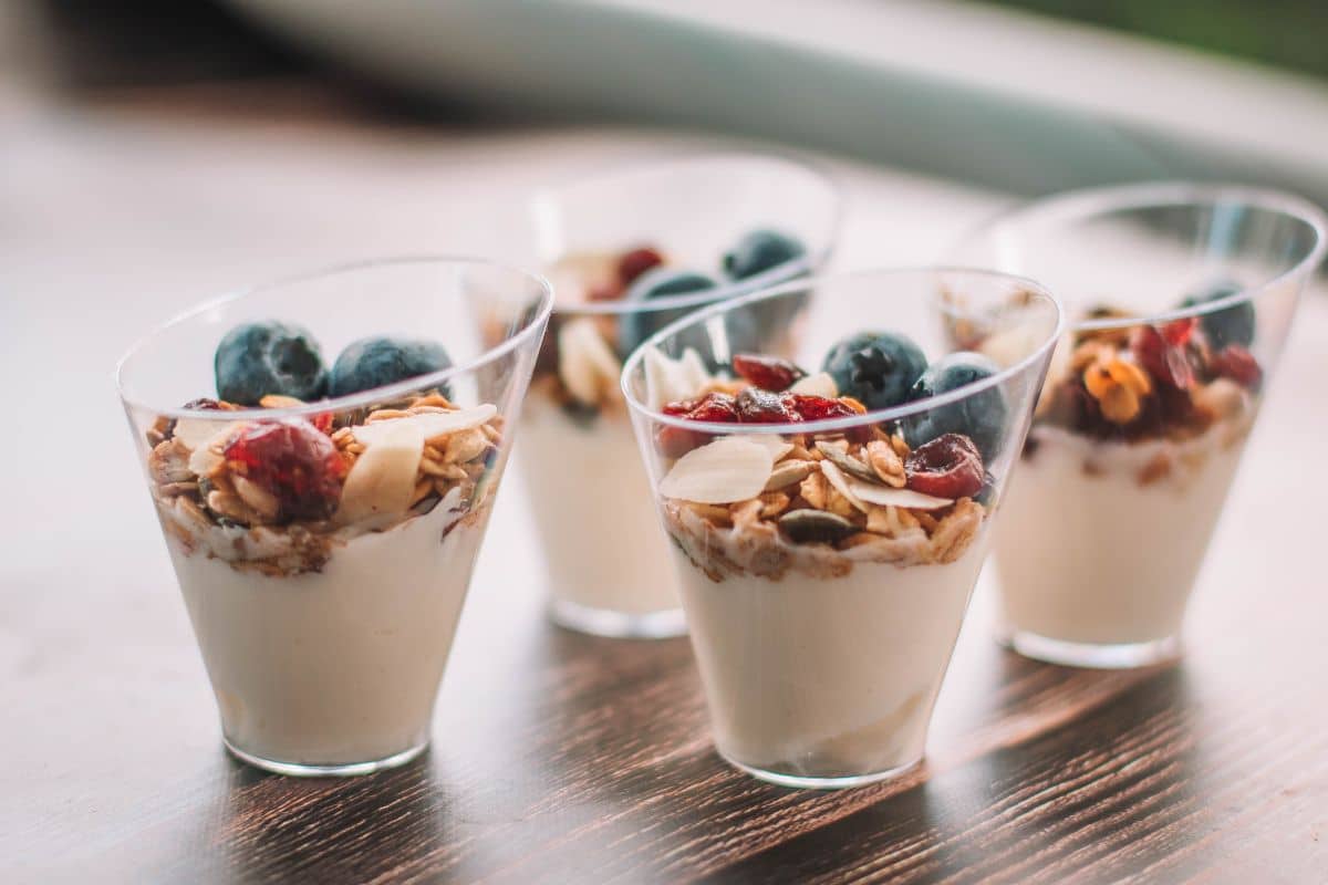 Glass cups of yogurt with oat flakes and fruits on table