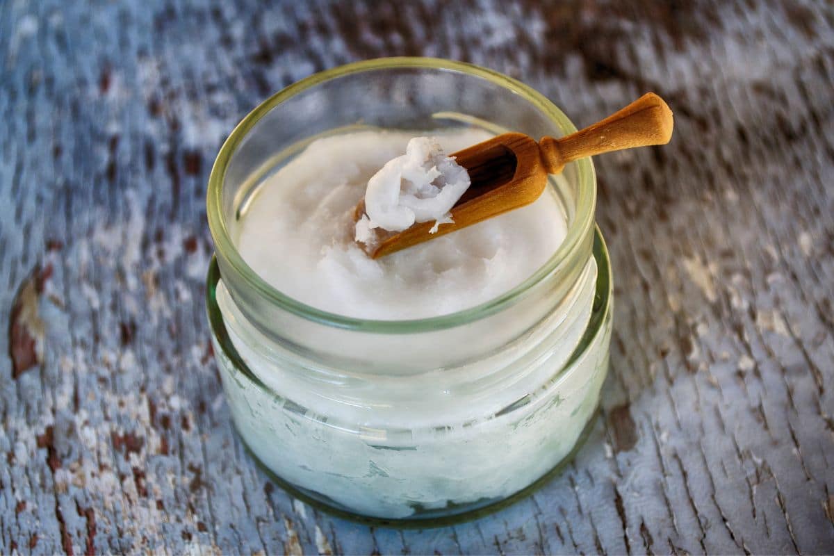 Glass jar with coconut oil and wooden spoon