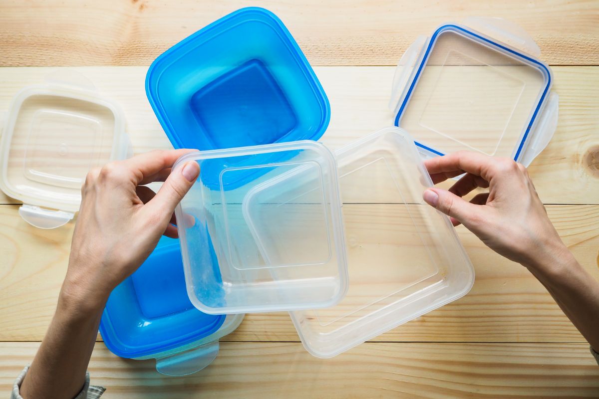 Hands holding plastic containers on wooden table