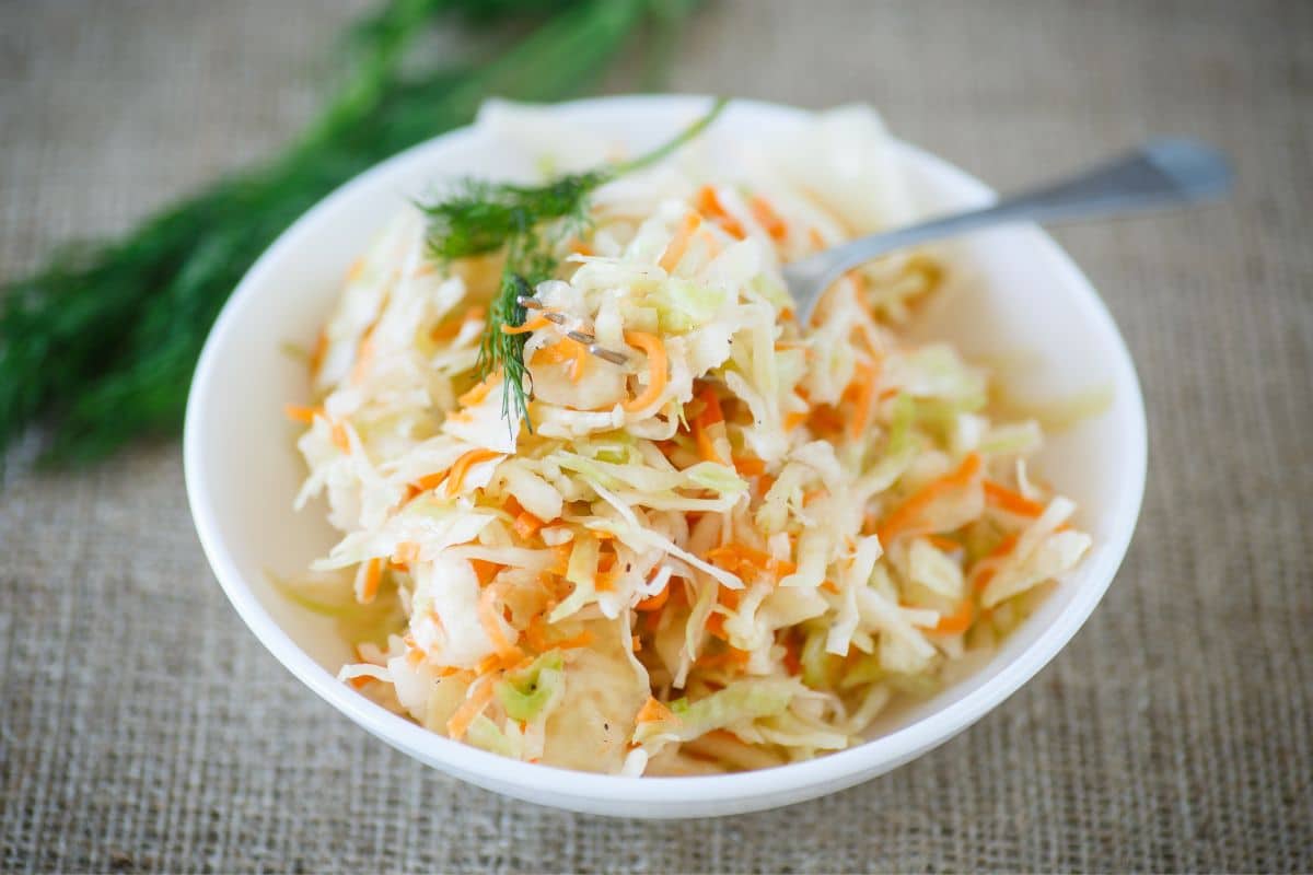 White bowl of Sauerkraut with fork on table