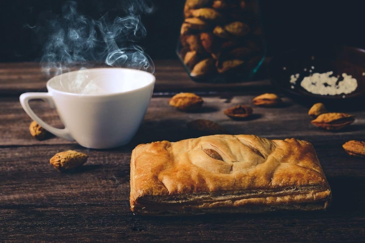 Apple hot pocket on table with cup of coffe and scattered pecans around