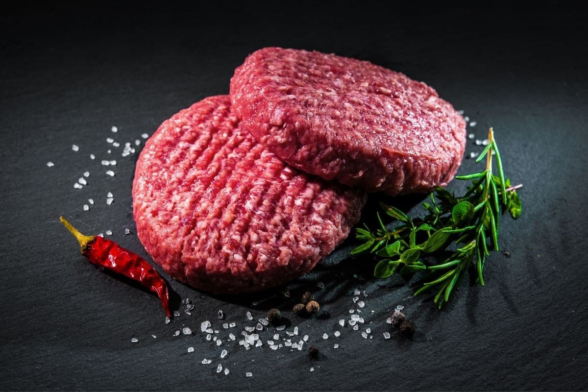 Beef hamburger pads with chilli, salt and herb on black table