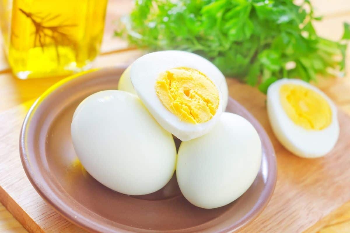 Boiled eggs on plate with herbs and bottle of oil on the table