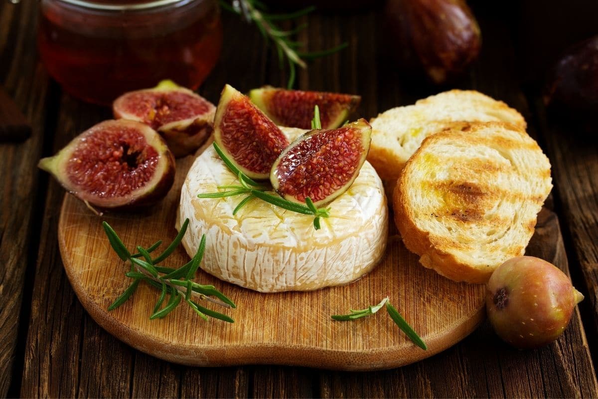Brie cheese with figs and bread on wooden board