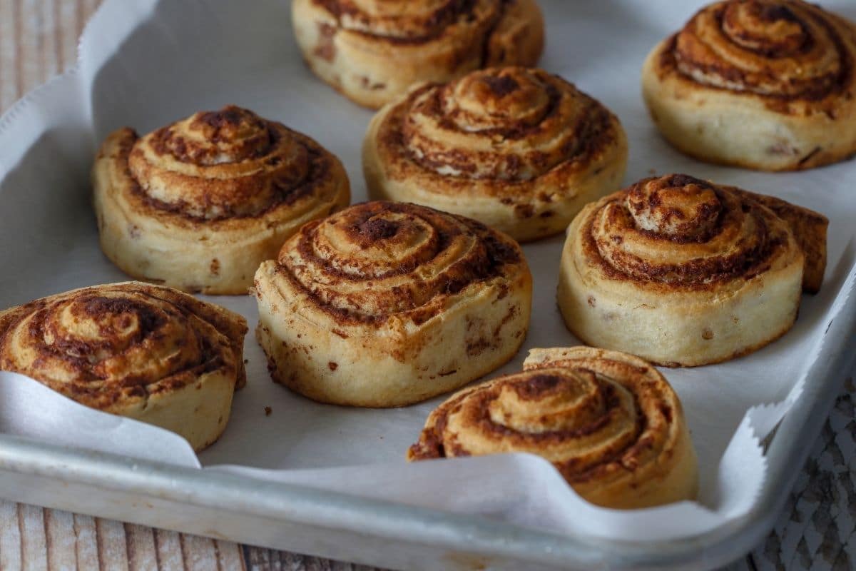 Cinnamon rolls on paper sheet on baking tray