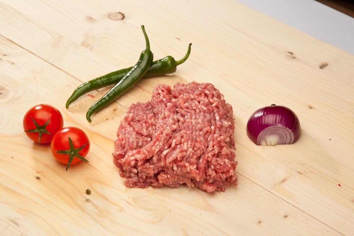 Ground turkey with tomatoes, onion, peppers on wooden board