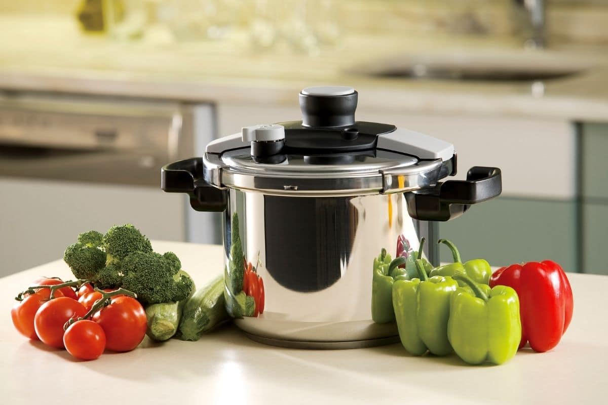 Pressure cooker with vegetables on white table