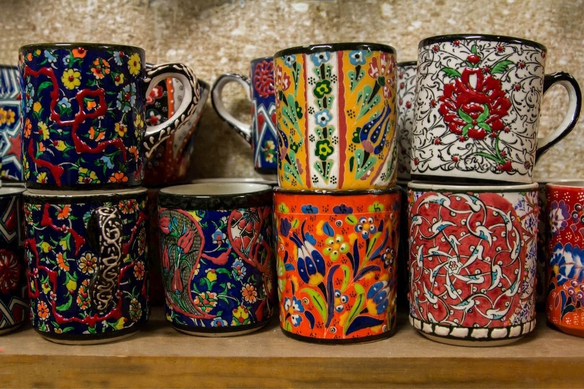 Colorful porcelain cups on wooden shelf