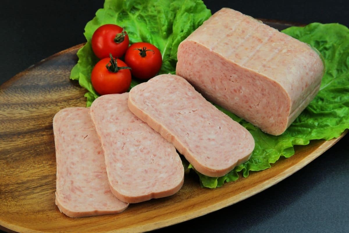 Spam lunch meatt sliced on wooden board with tomatoes and saald