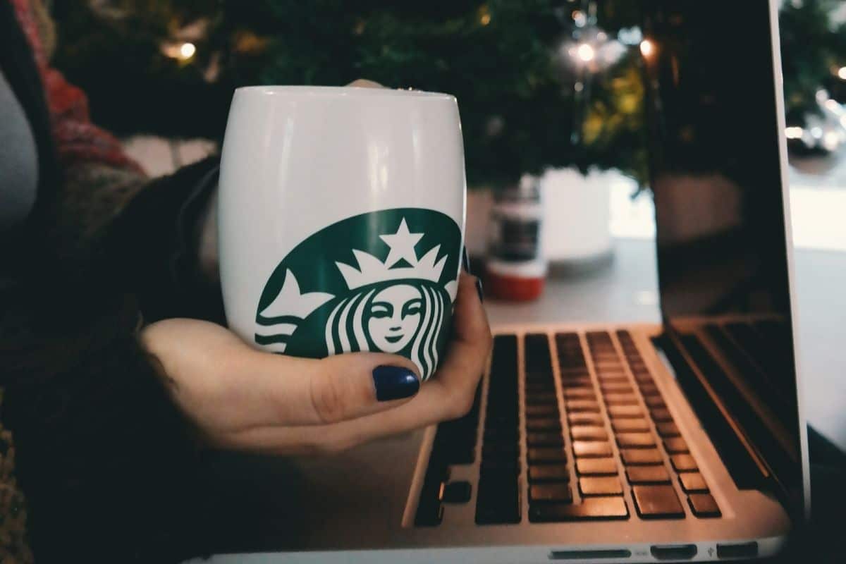 Woman holding starbucks ceramic mug over laptop