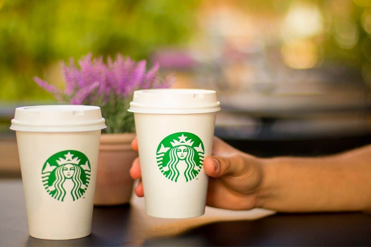 Hand holding starbucks cup, another cup on table