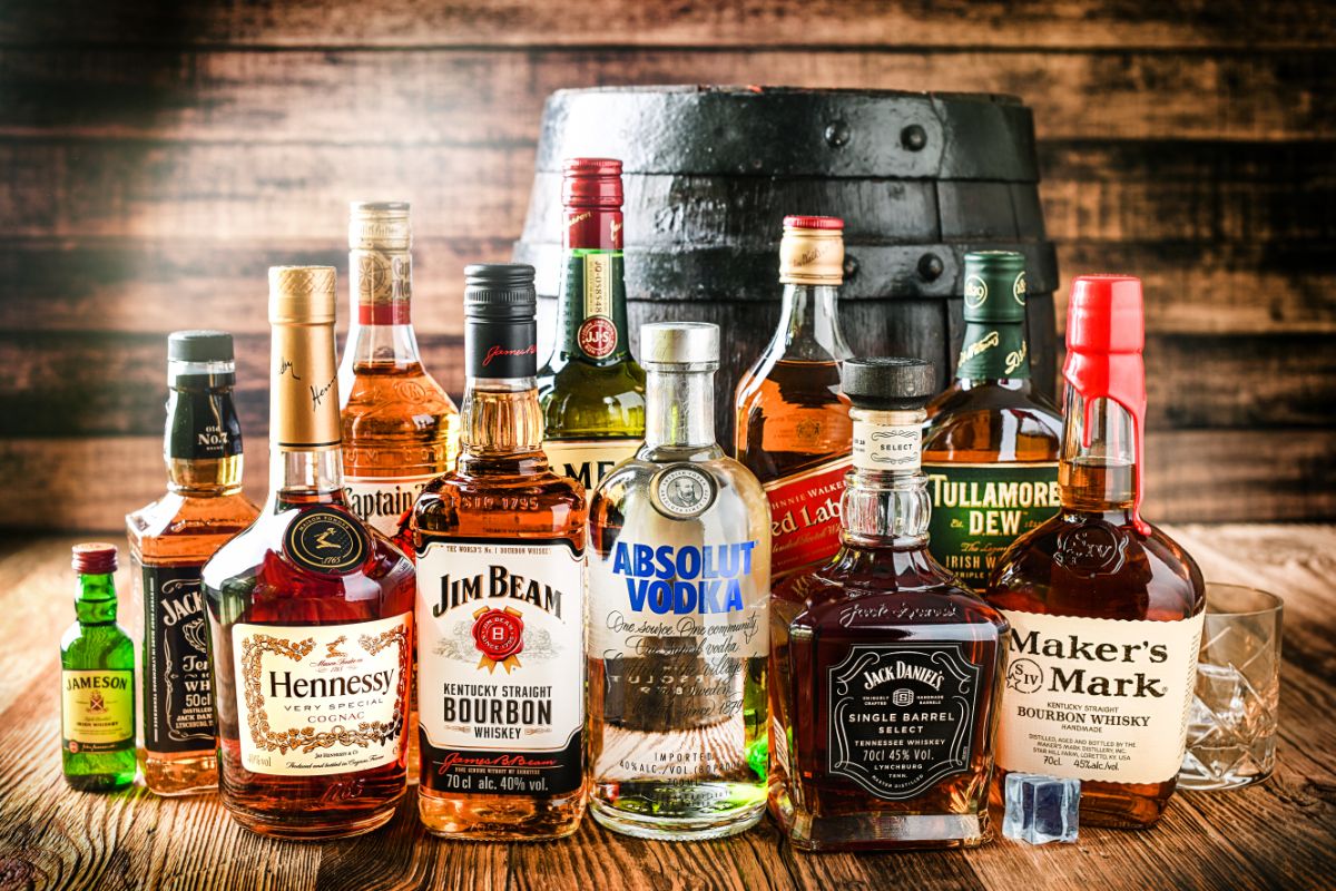 Different varieties of alcohol bottles and barrel on a table.