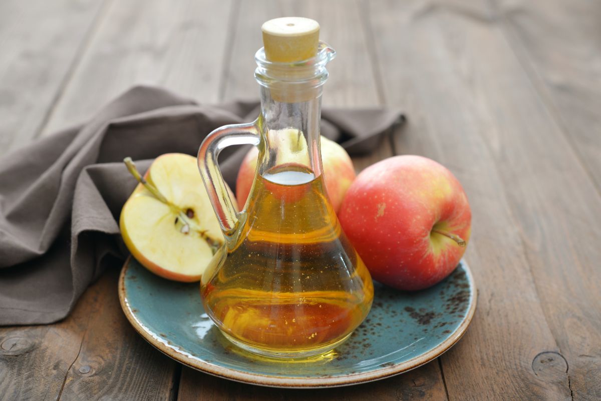 Bottle of apple cider with  fresh apples on a blue plate on a wooden  table.