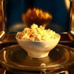 White bowl of popcorn in a microwave.