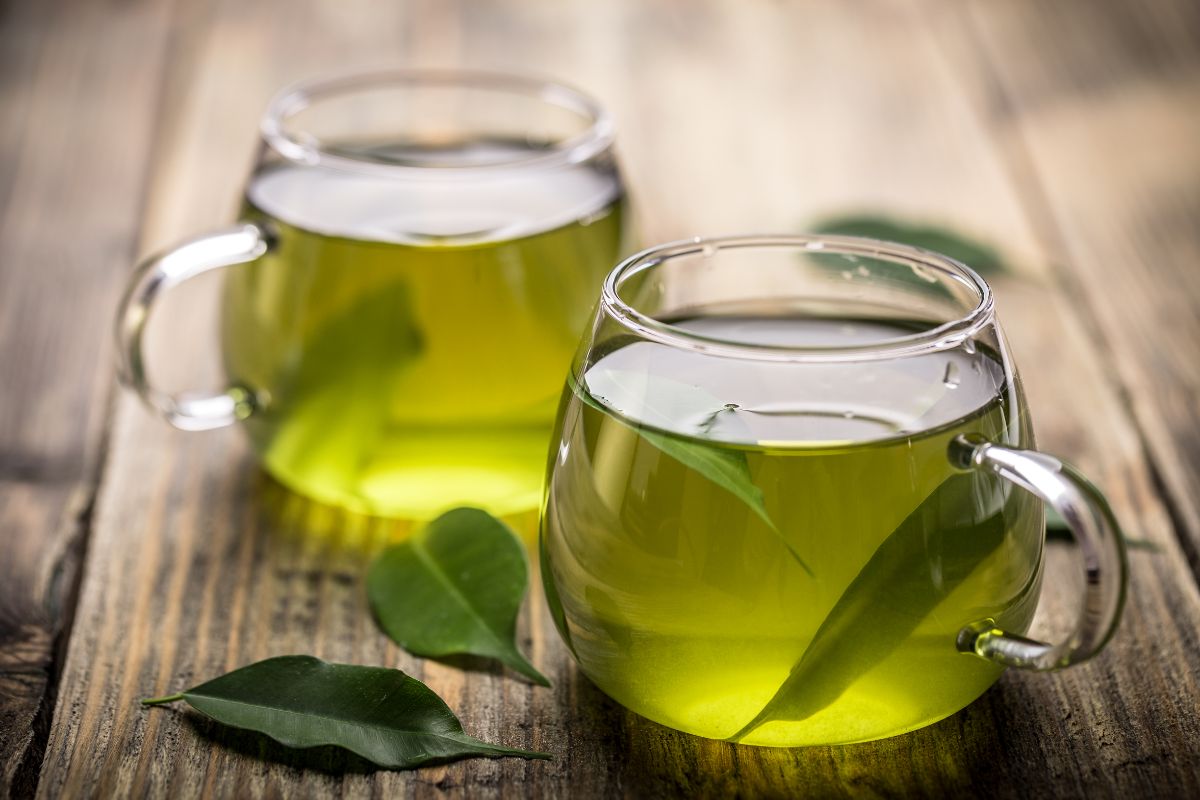 Two cups of green tea on a wooden table.