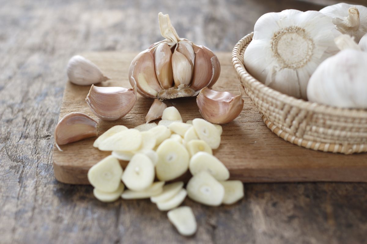 Trimmed garlic and garlic heads on a wooden cutting board.